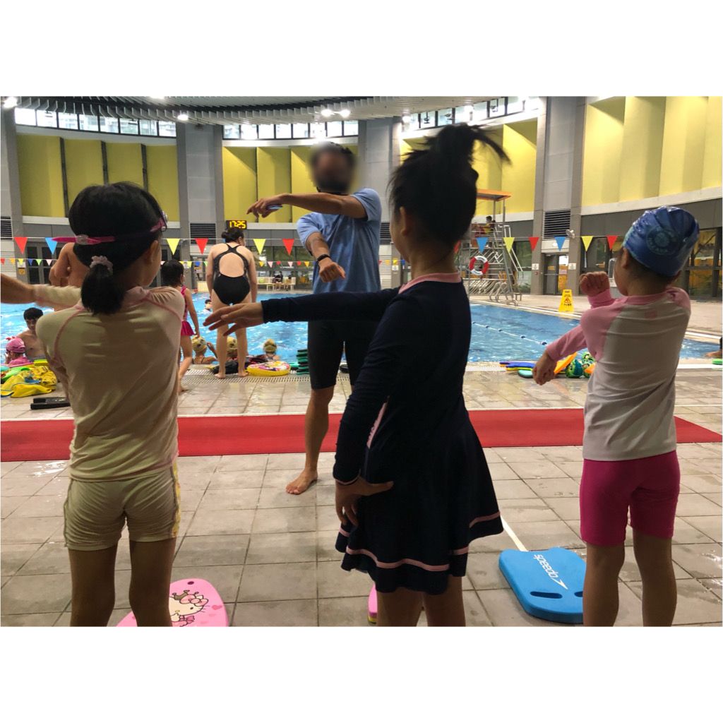 教練帶著女兒和朋友仔一起做游泳前的熱身運動
