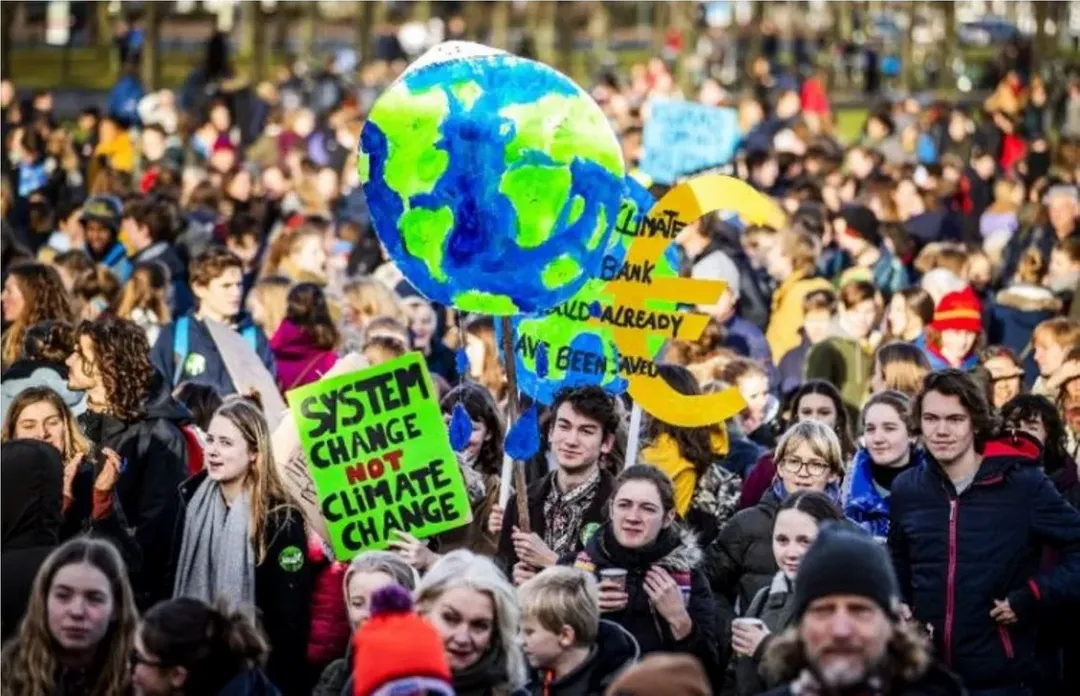 2019年，新一代的環保抗議者，標語牌上寫著：「要體制變化，不要氣候變化」。 （圖片來源：Remko de Waal, AFP）